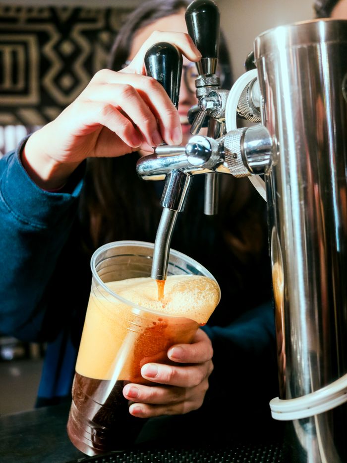 Barista filling a cup of nitro cold brew coffee from a tap in a cozy café setting.