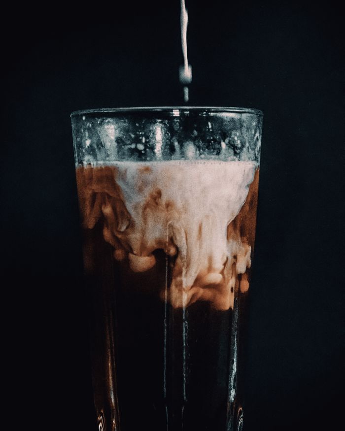 Elegant shot of milk swirling into a glass of iced coffee, creating a delicious blend.